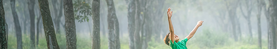 Boy jumps for joy in forest