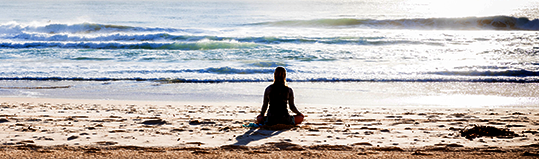 Sillhouette of woman mediating on beach